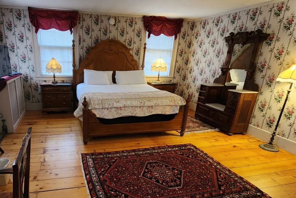 Pamela's Suite: carved canopied bed with floral wallpaper