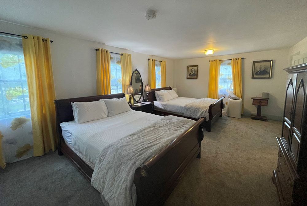 Adelia's Room: two dark-wood beds with portrait paintings