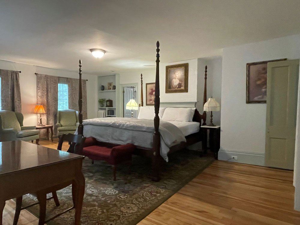 Justin James' Suite: four-poster bed with red chaise and portrait paintings